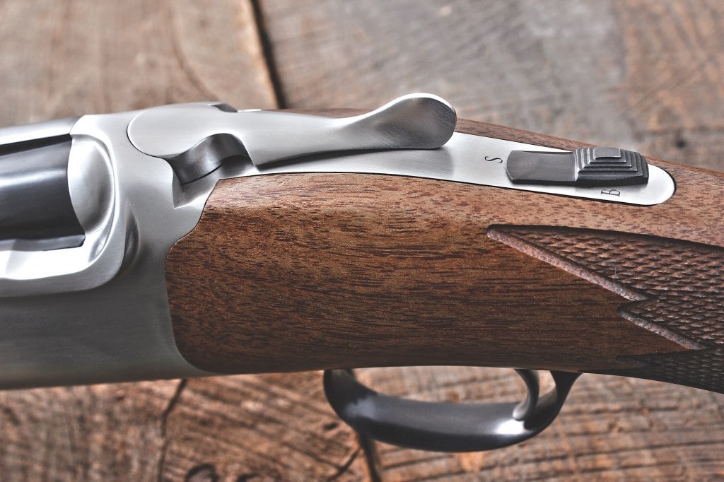 the new gun preserves the look of the original, with subtle aesthetic variations—including a stainless lever in place of what was historically blued. a two-position safety button doubles as a barrel selector when toggled side-to-side.